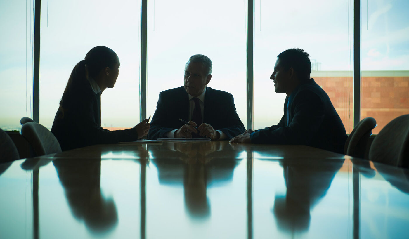Executives in silhouette around a boardroom table